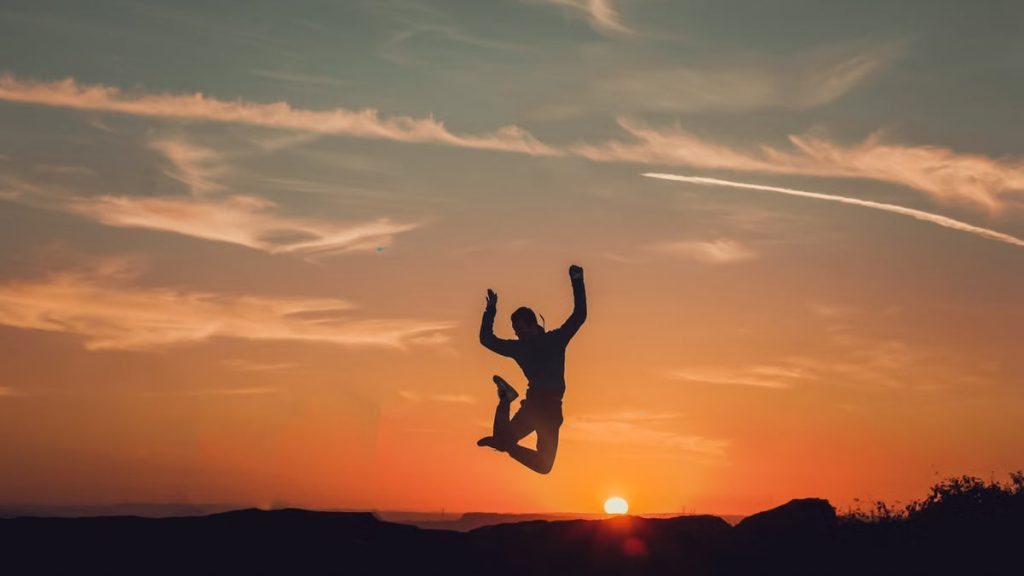 A person silhouetted against a stunning sunset, capturing a moment of freedom and joy.